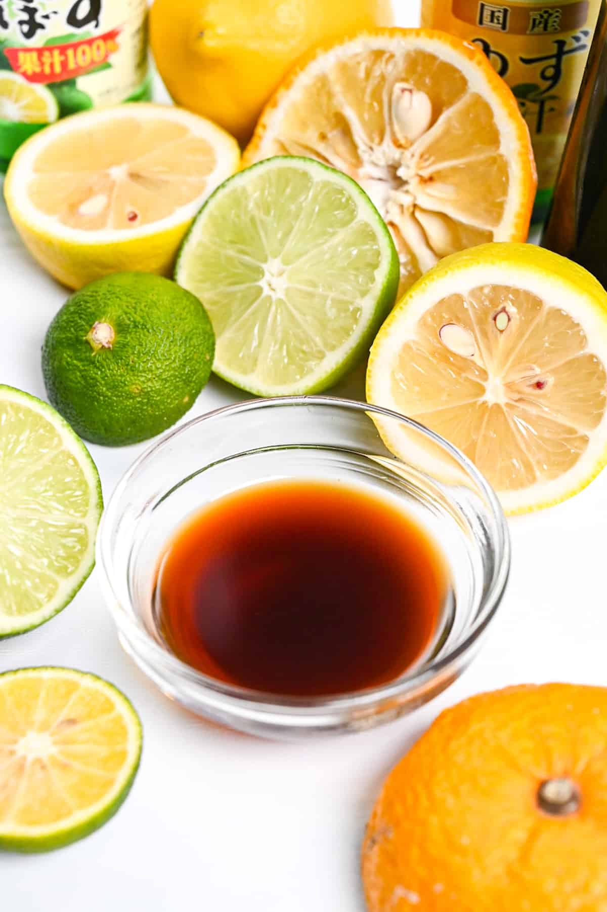 Ponzu sauce in a small glass bowl surrounded by citrus fruits