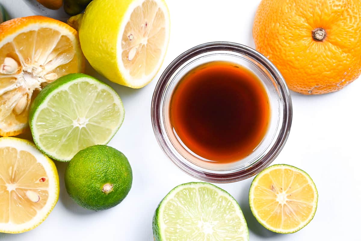 Ponzu sauce in a small glass bowl surrounded by citrus fruits