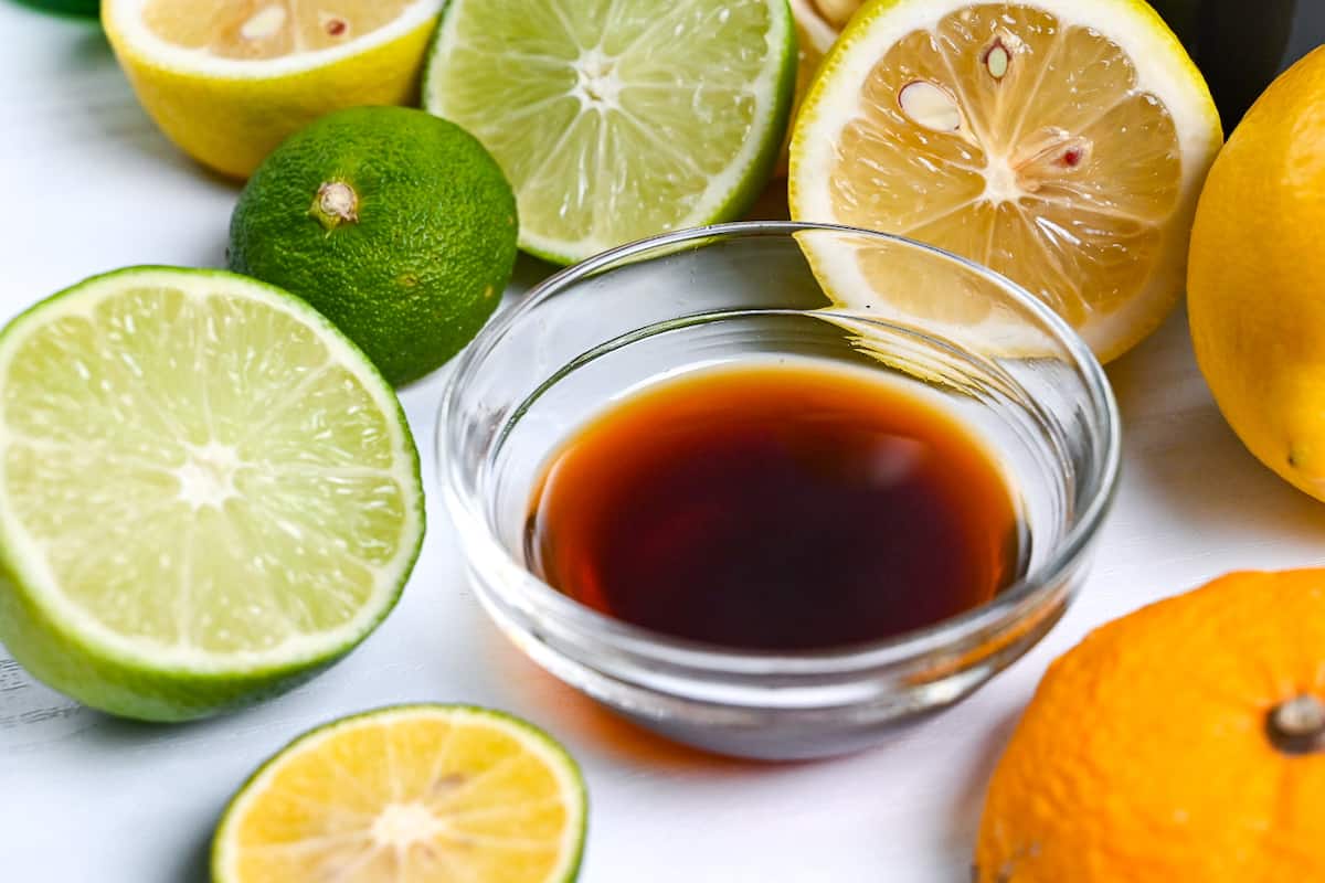 Ponzu sauce in a small glass bowl surrounded by citrus fruits