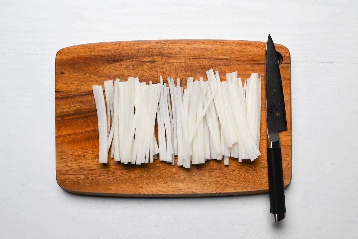 daikon radish cut into matchsticks on a wooden chopping board