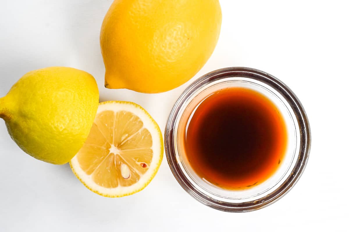 Lemon ponzu in a small glass bowl next to a sliced lemon