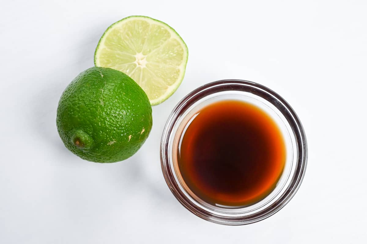 Lime ponzu in a glass bowl next to a cut lime