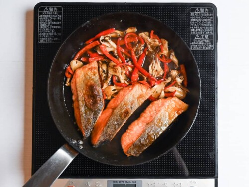 Salmon, bell peppers and maitake mushrooms in a frying pan