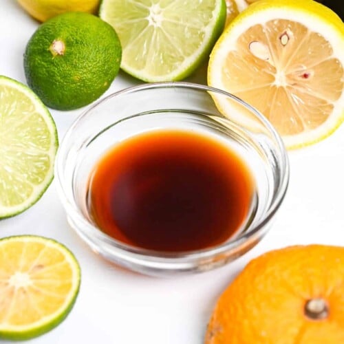 Ponzu sauce in a small glass bowl surrounded by citrus fruits