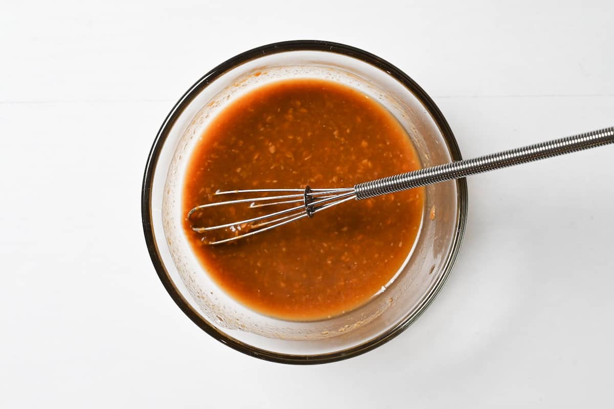 Miso paste mixed with cooking liquid and soy sauce in a small glass bowl