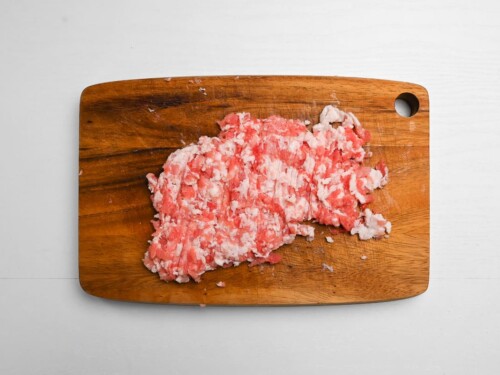 Finely diced pork belly on a wooden chopping board