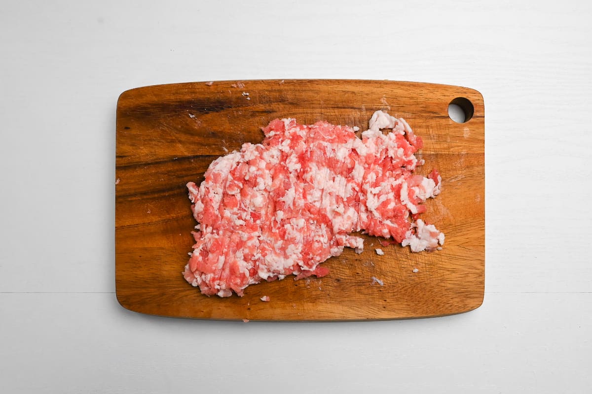 Finely diced pork belly on a wooden chopping board