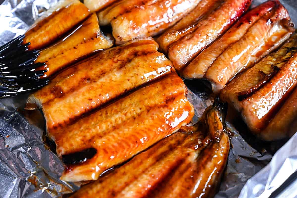 eel fillets being brushed with unagi sauce