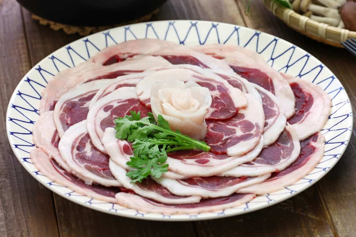 Thin slices of boar meat arranged on a plate in the shape of a peony flower