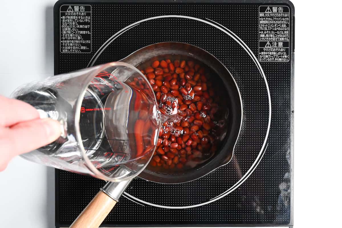 Adding fresh water to adzuki beans in a pan