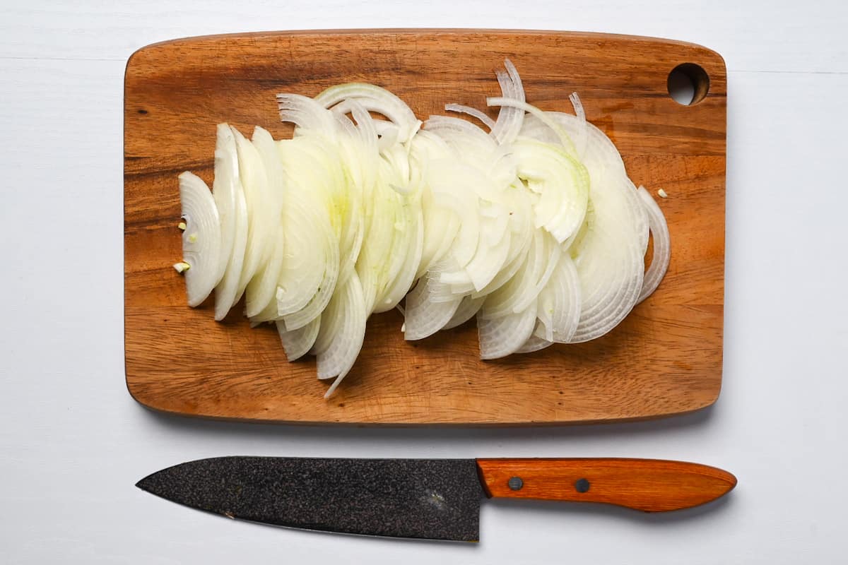 Thinly sliced onion on a wooden chopping board