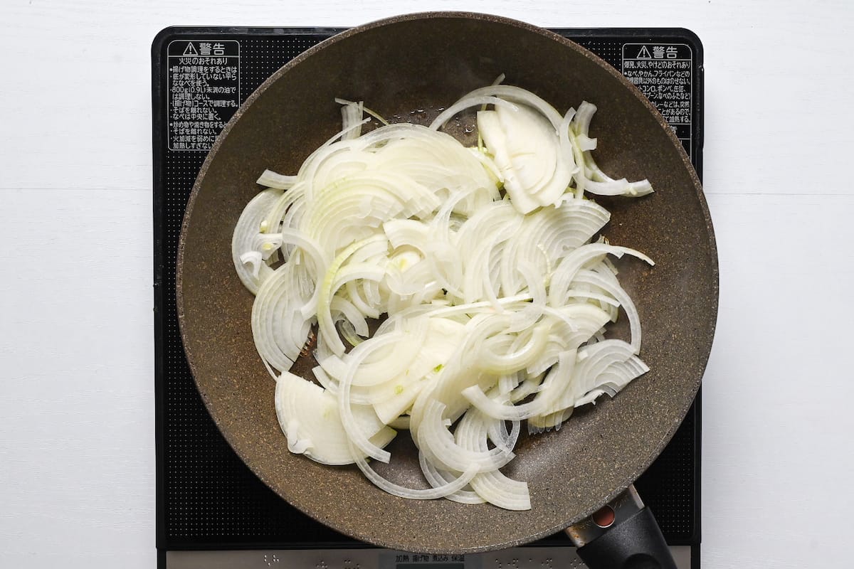 Thinly sliced onion in a pan with oil