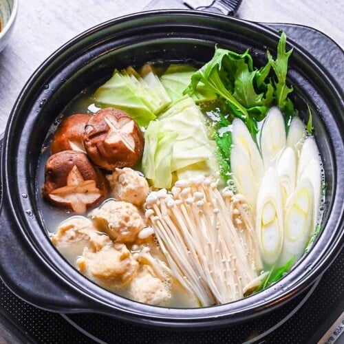 Hakata Chicken Mizutaki in a hot pot with homemade chicken meatballs, enoki, shiitake, cabbage, mizuna and spring onion in a rich chicken and kombu broth