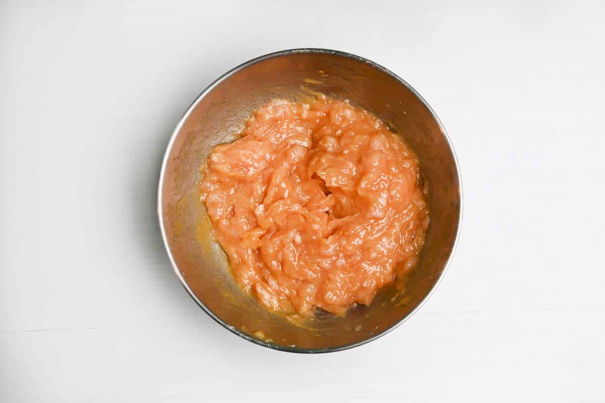 Chicken meatball mixture in a silver mixing bowl