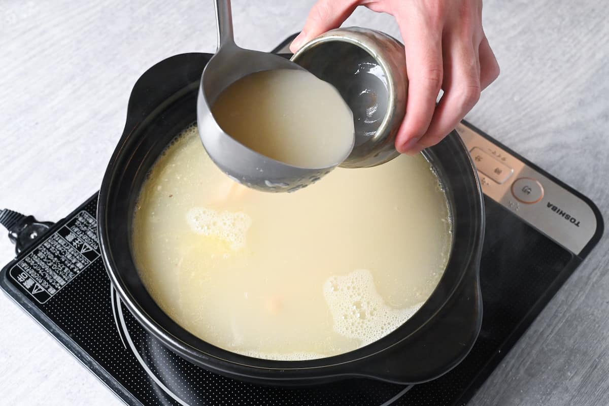 Chicken broth in a Japanese nabe (hot pot) on a portable stove