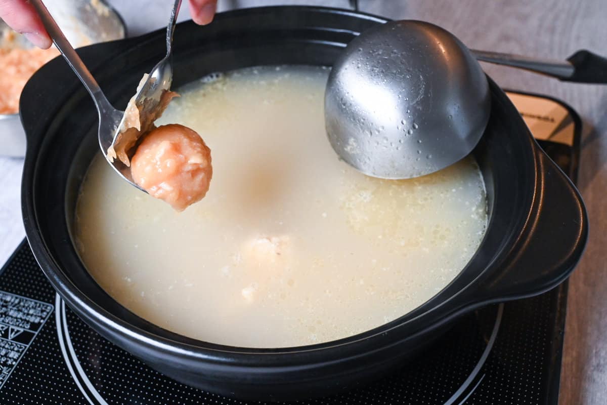 Adding chicken meatballs to mizutaki broth