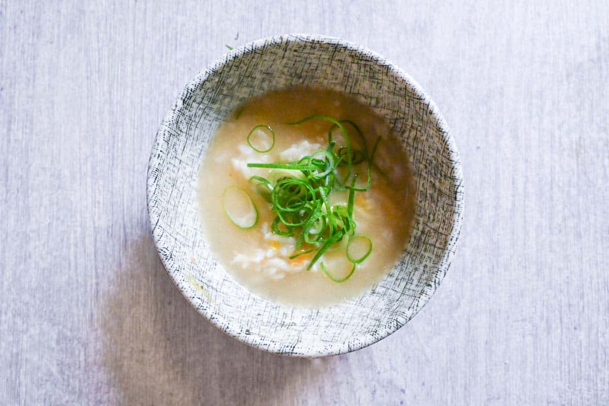 Rice and egg in mizutaki broth topped with chopped spring onion