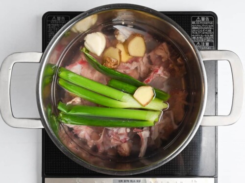Chicken bones, spring onion, ginger and garlic in a pot of water