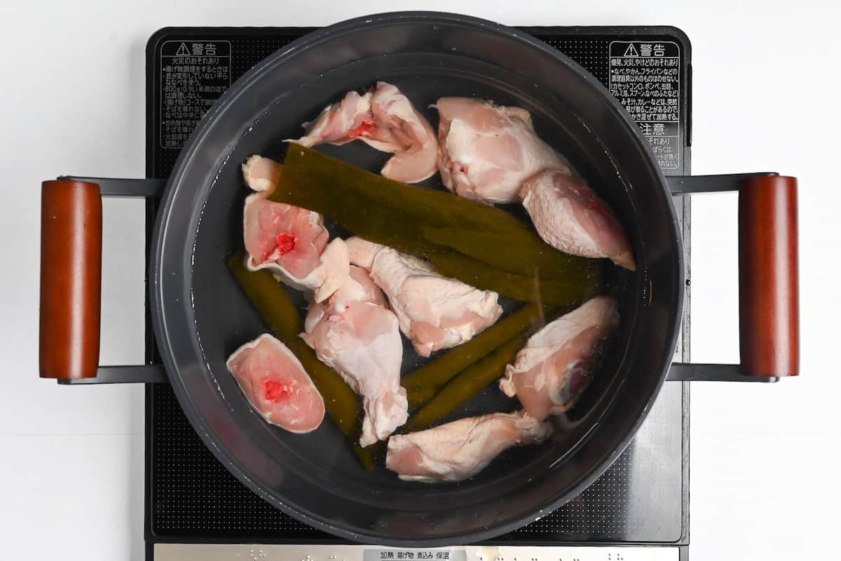 Chicken meat and kombu in a pan of water