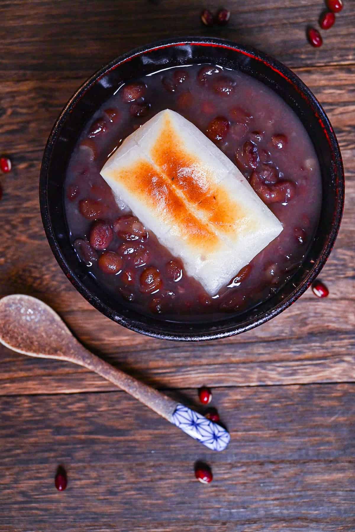 Zenzai (Japanese red bean soup) served in a black bowl and topped with toasted kirimochi