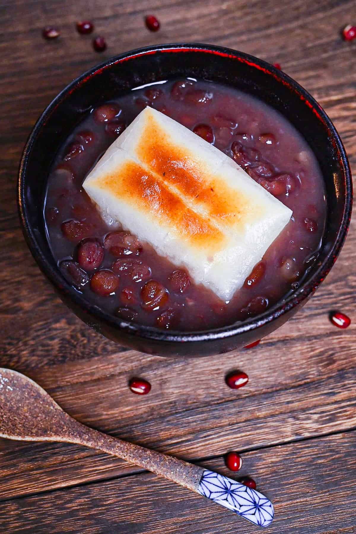 Zenzai (Japanese red bean soup) served in a black bowl and topped with toasted kirimochi