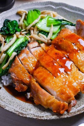 Crispy chicken steak drizzled with ponzu sauce served with rice and sautéed vegetables on a beige plate