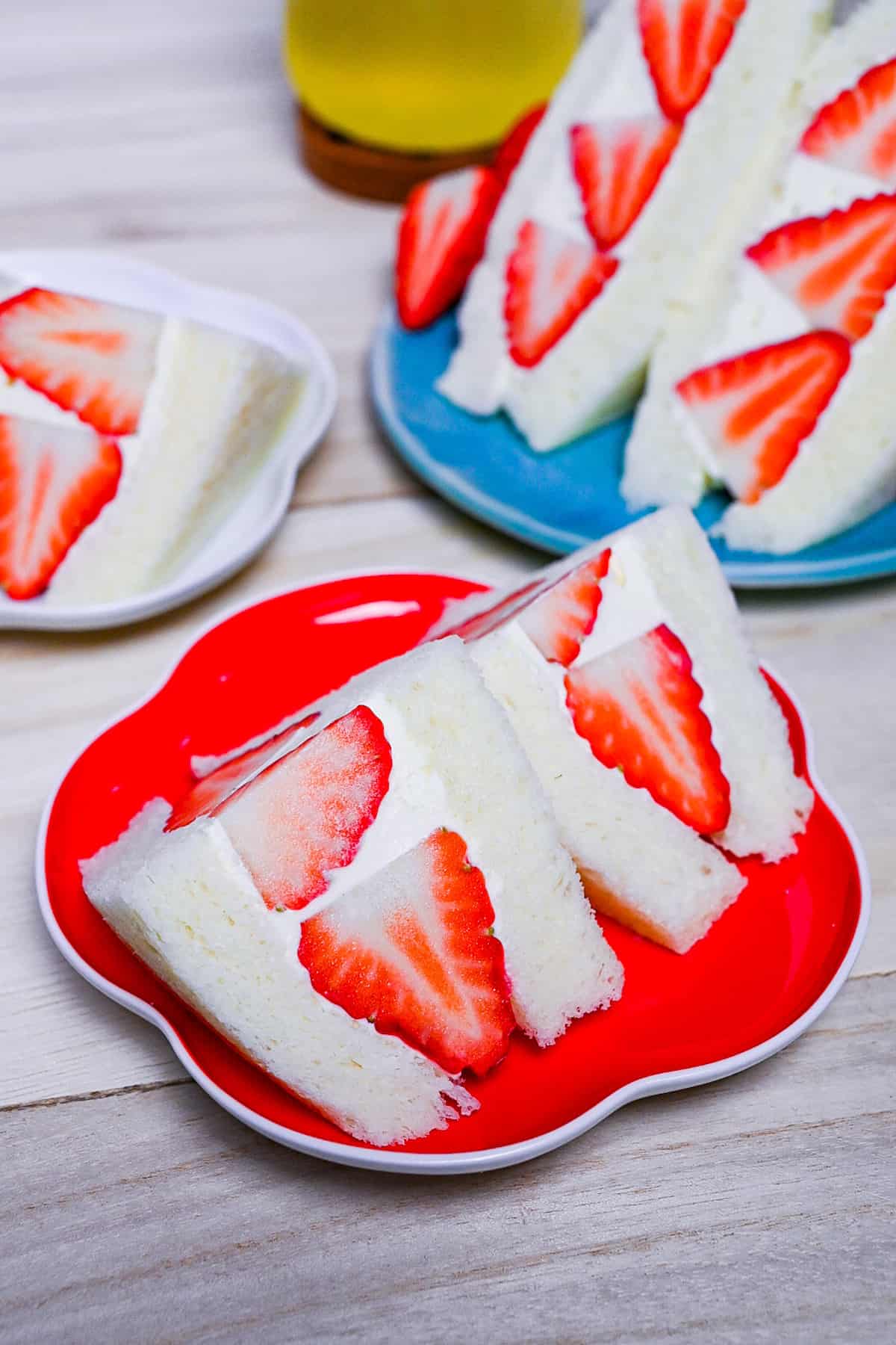 Japanese ichigo sando (strawberry sandwich) cut into triangles on a red flower shaped plate