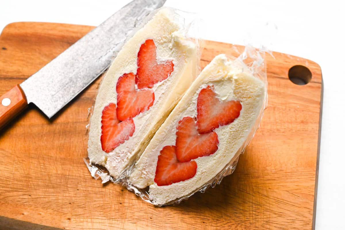 Ichigo sando with heart shaped strawberries on a wooden chopping board