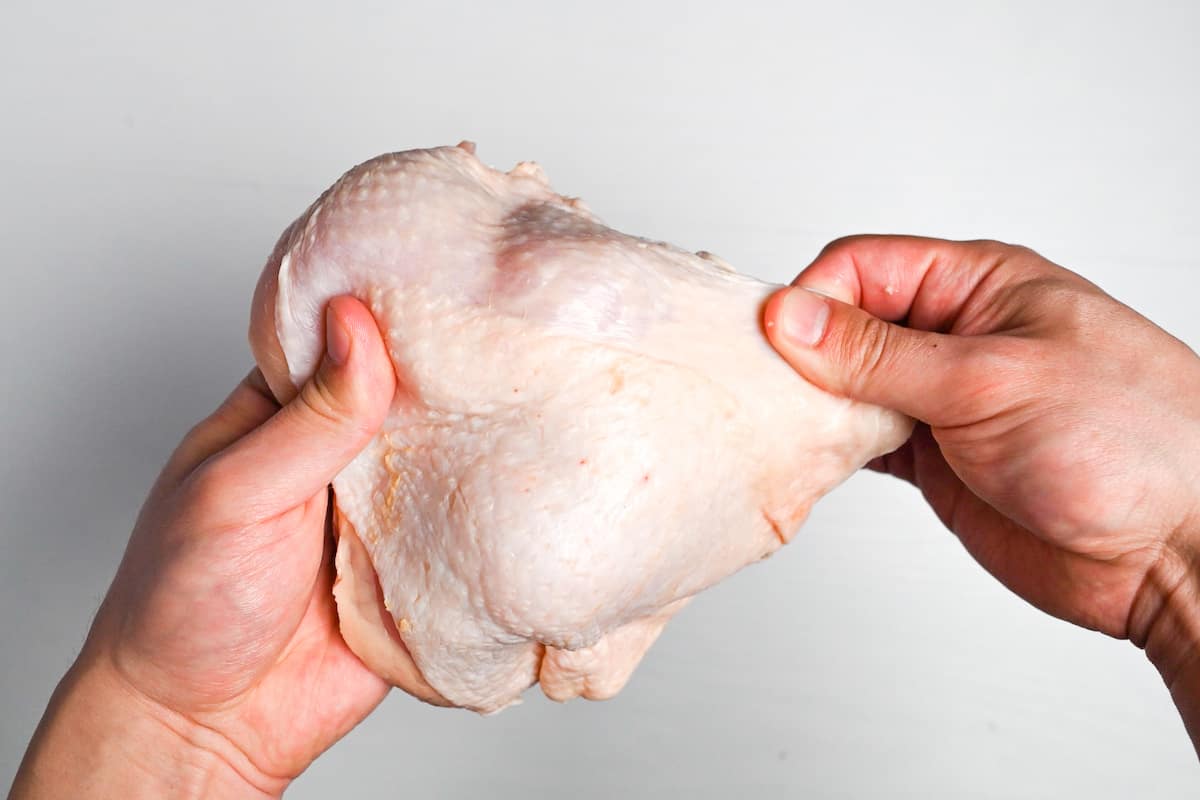 Pulling the skin of the chicken over the edges