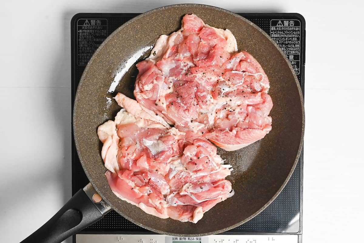 2 chicken thighs in a large frying pan with the skin side down