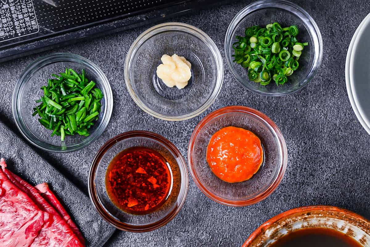 Additional ingredients for shabu shabu sauces (chives, grated garlic, spring onion, chili oil and momiji oroshi)