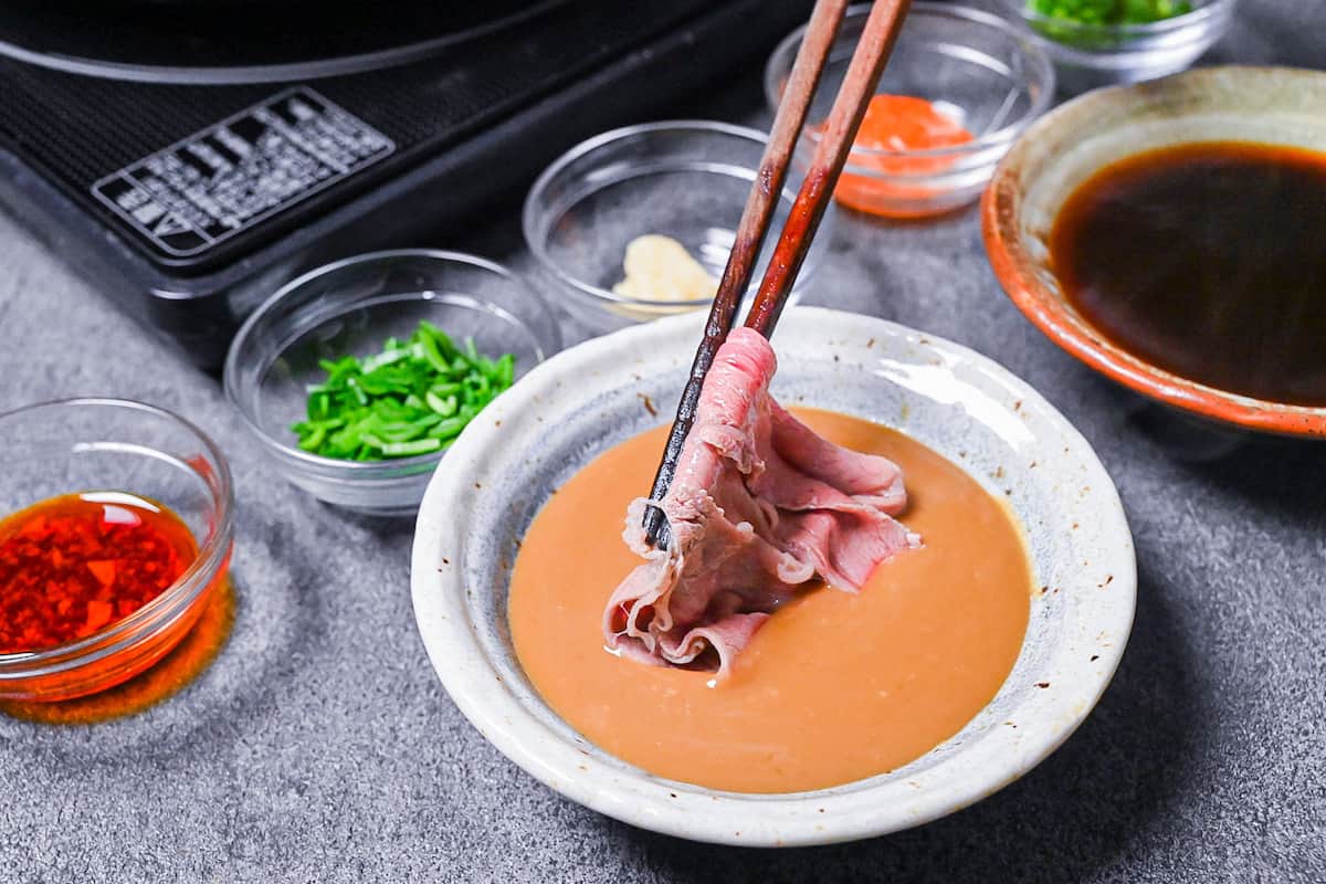 dipping cooked wagyu beef in shabu shabu sesame sauce