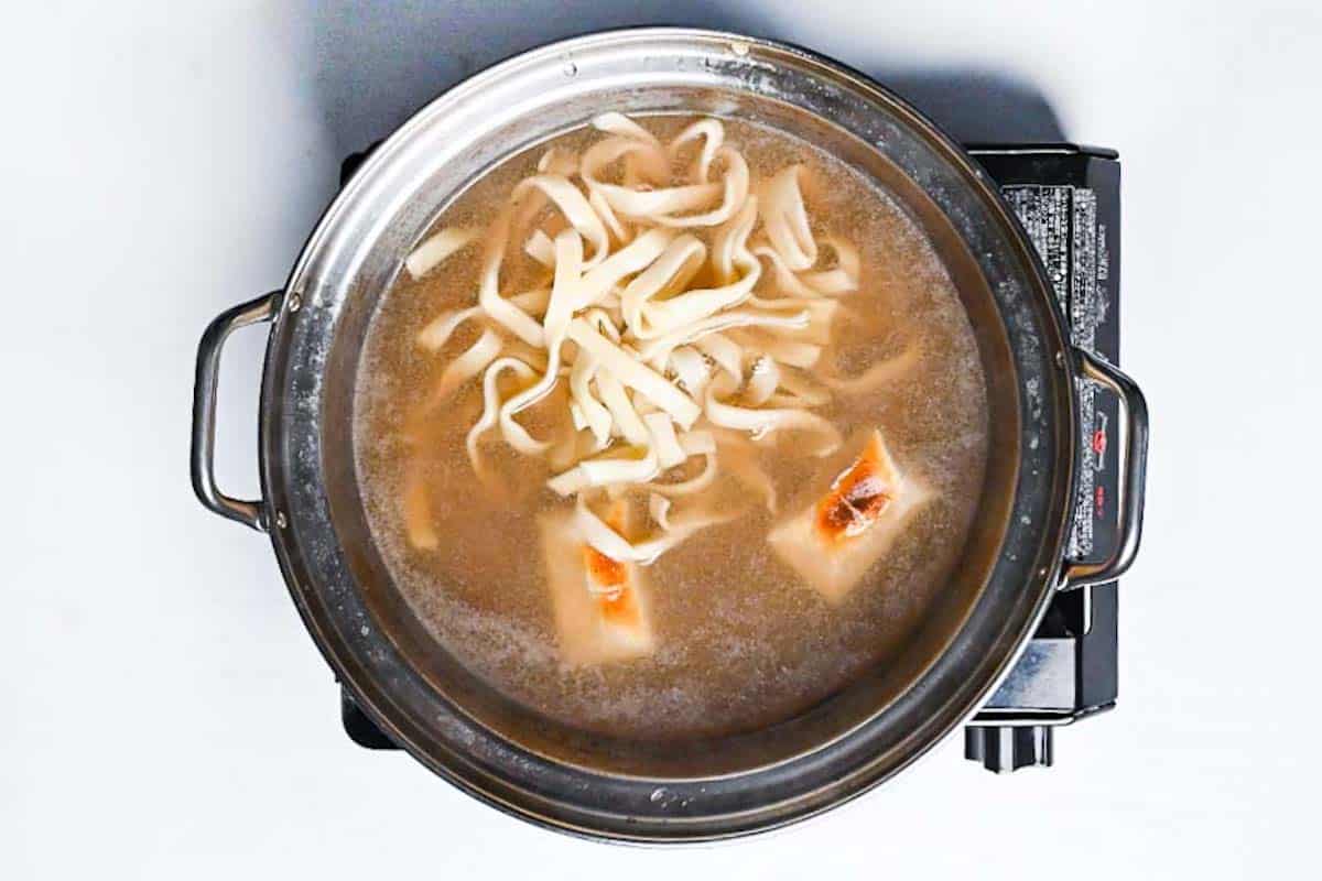 cooking noodles and toasted mochi in shabu shabu broth