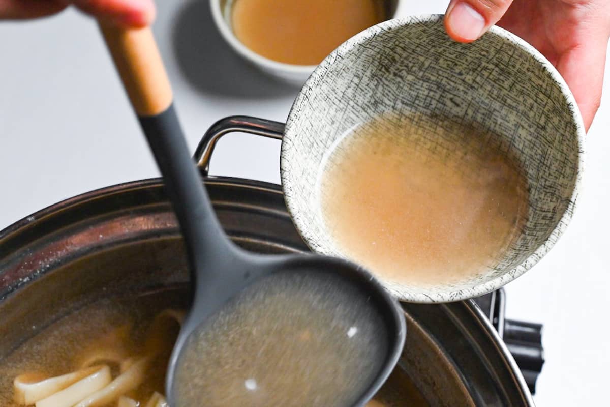 Pouring shabu shabu broth into individual serving bowls.