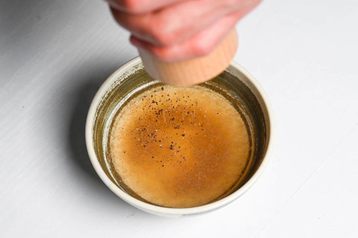 Sprinkling black pepper into shabu shabu broth.