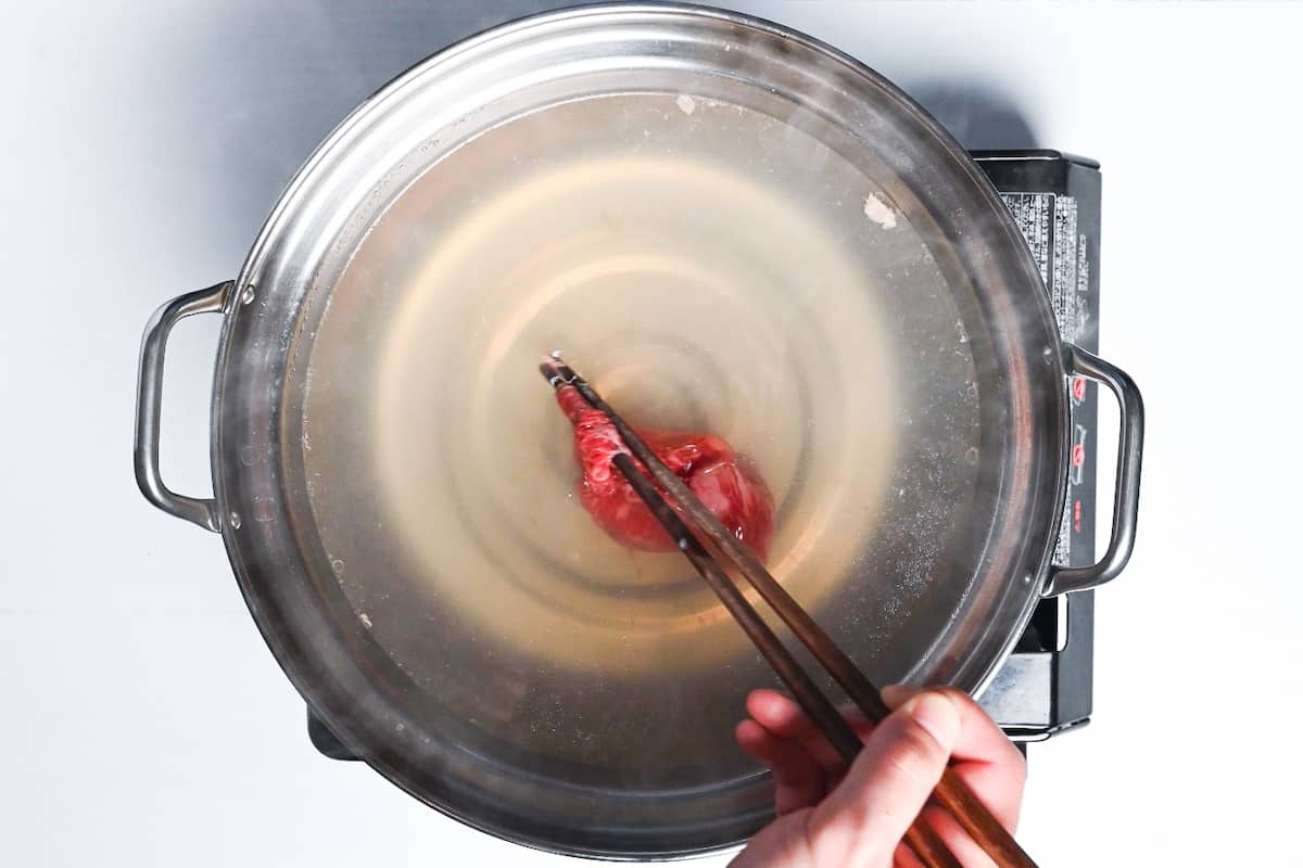 Cooking thinly sliced wagyu beef in kombu dashi by swishing with chopsticks