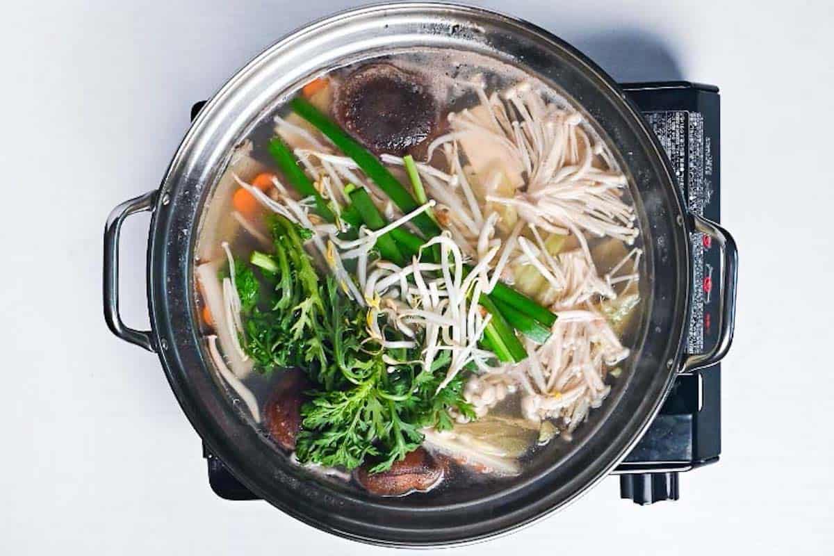 adding beansprouts, chives and shungiku to shabu shabu pot