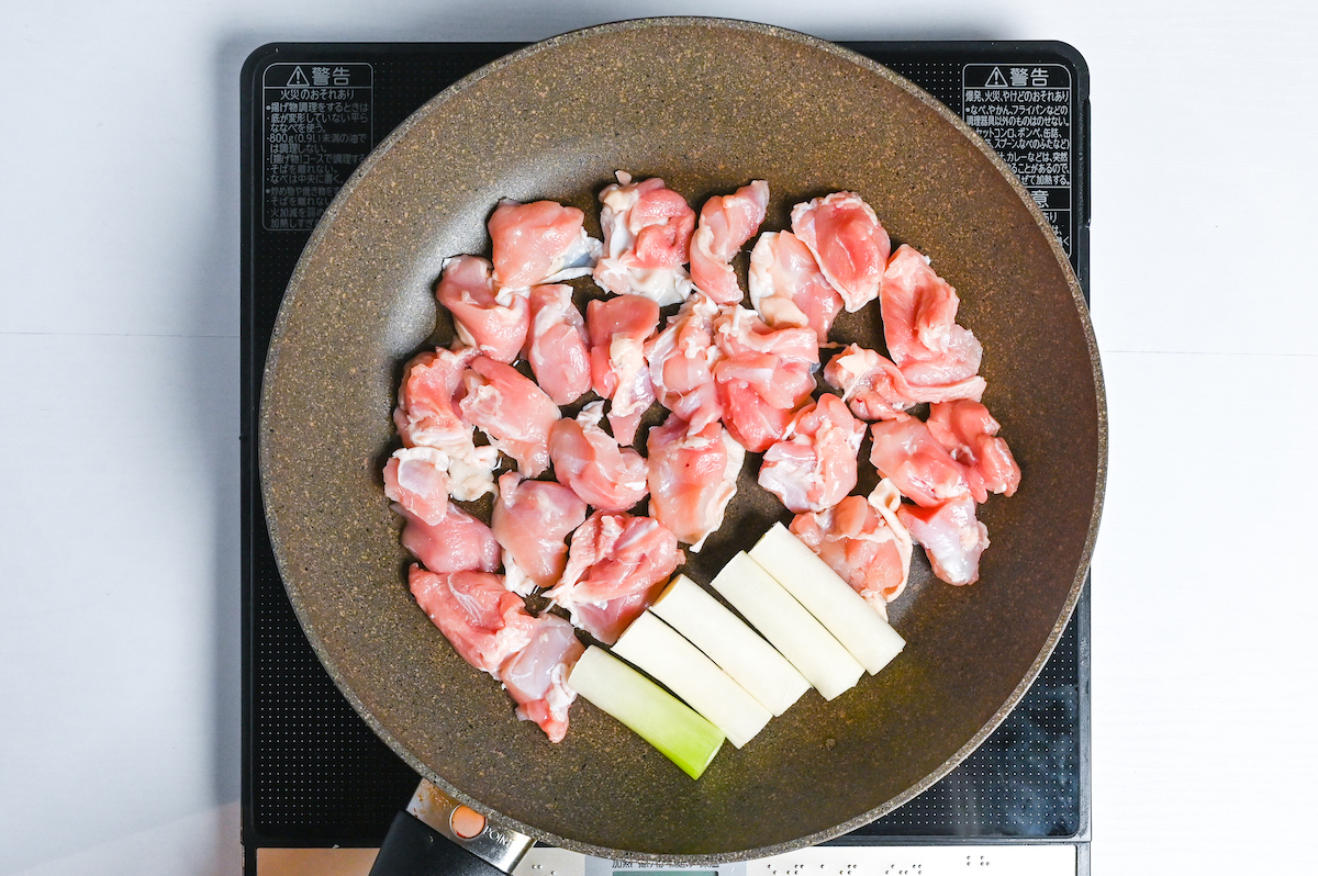Frying chicken and spring onion in a large frying pan