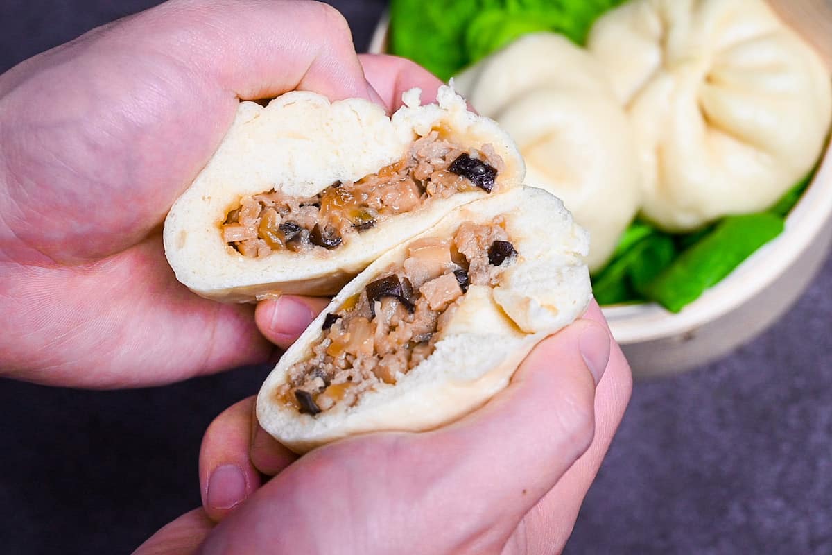 Japanese pork nikuman cut in half and held in hand