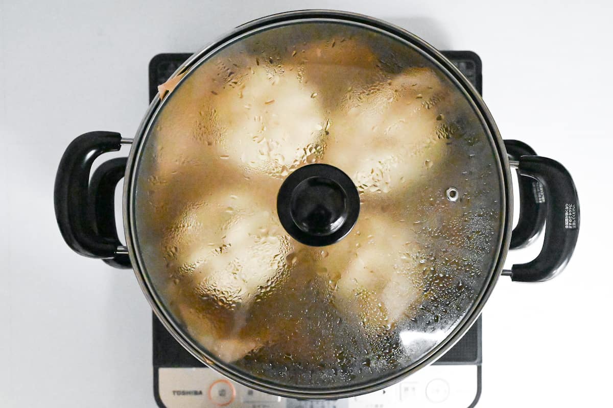 4 nikuman (Japanese pork steamed buns) steaming in a steel steamer