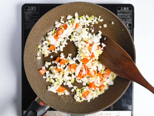 Diced onion, carrot, celery and garlic frying in a frying pan with melted butter