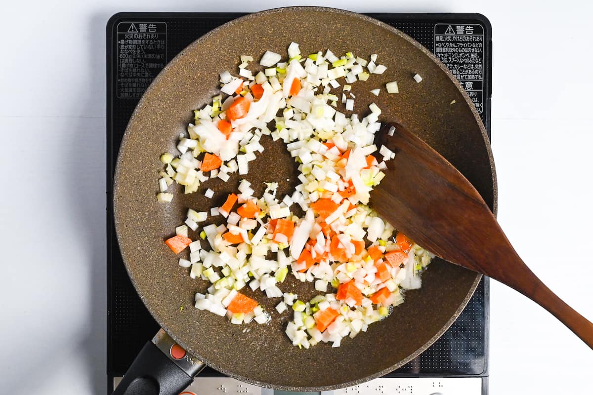 Diced onion, carrot, celery and garlic frying in a frying pan with melted butter