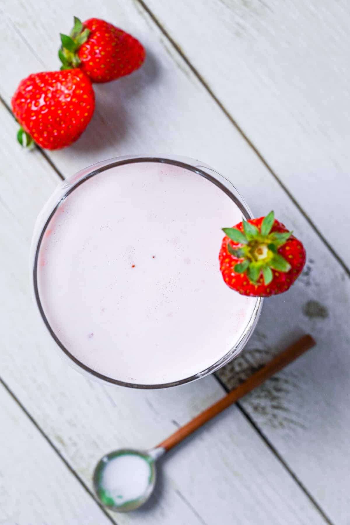 Japanese strawberry milk in a glass with a strawberry on the rim top down