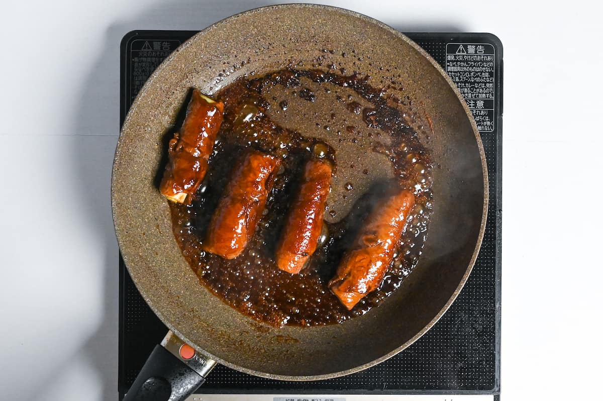 beef negimaki frying in sauce in a frying pan