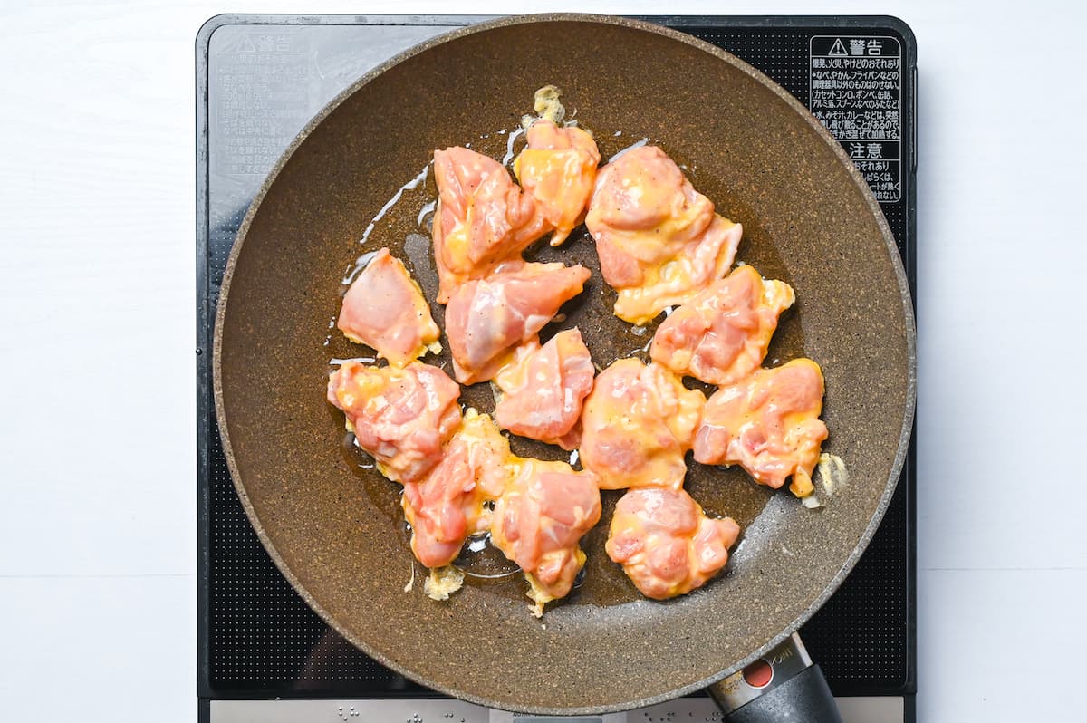 Frying chicken with egg batter in a frying pan