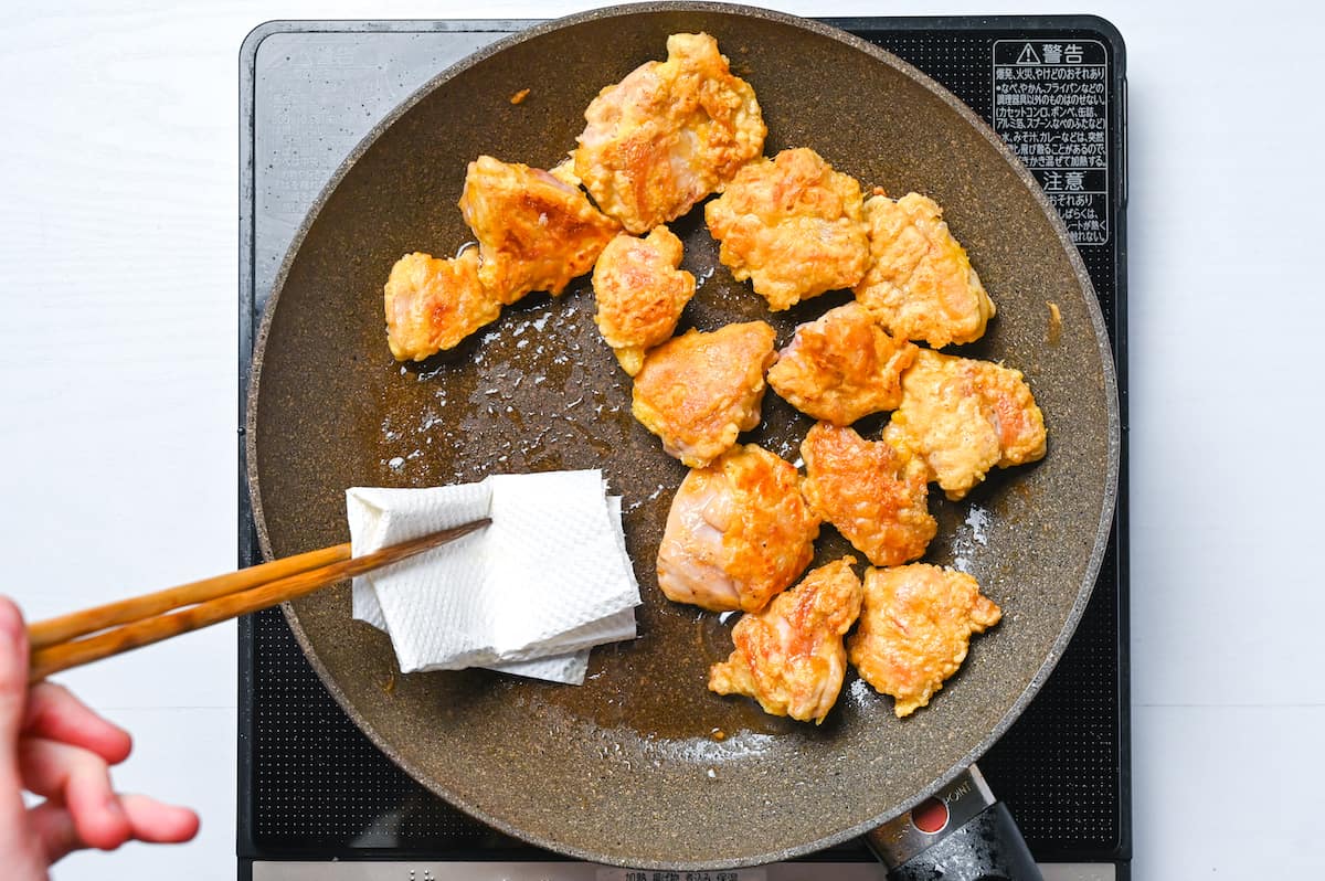 Wiping excess oil out of the frying pan using kitchen paper