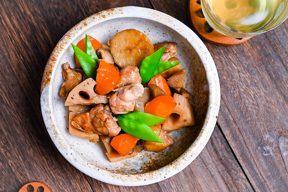 Chikuzenni (Japanese simmered chicken and vegetables) served in a mottled beige bowl top down