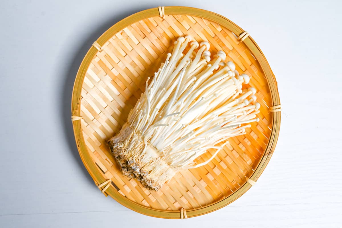 enoki mushrooms on a round woven bamboo tray