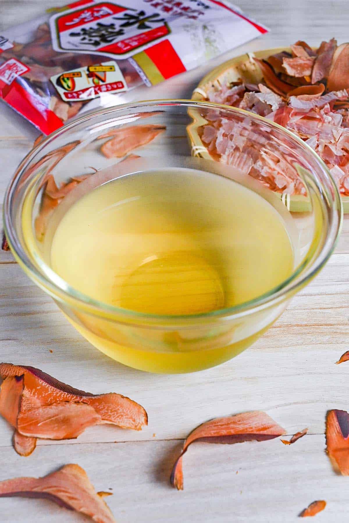 Katsuo (bonito flake) dashi in a glass bowl surrounded by bonito flakes