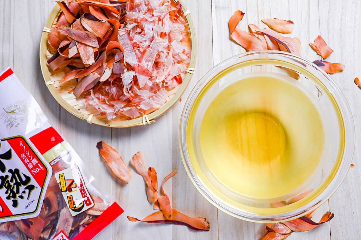 Katsuo (bonito flake) dashi in a glass bowl surrounded by bonito flakes